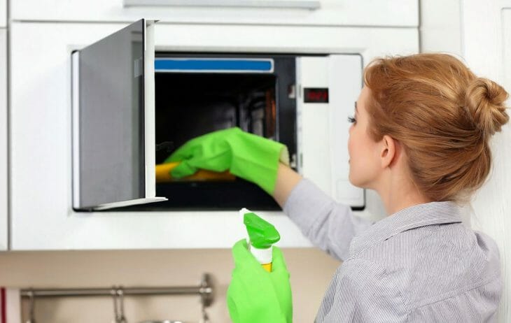 Женщина чистит микроволновую печь внутри